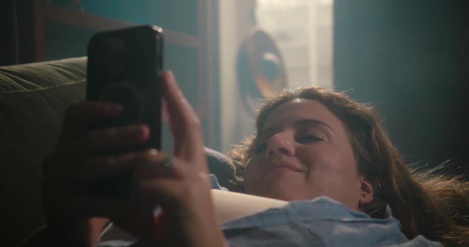 A teenage girl laughs as she swipes on her cell phone