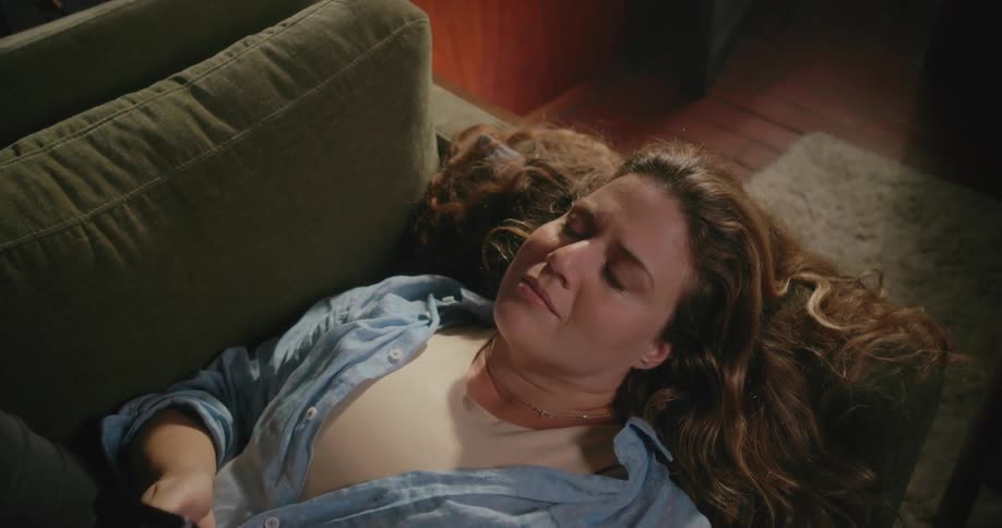 A woman is laying on a couch and looking at her cellphone