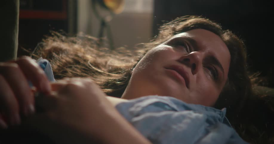 A sad woman crying and shaking her head while lying on a couch