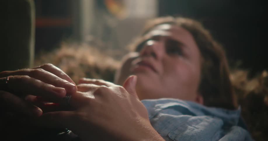A sad looking woman lies on her back and plays with her wedding ring
