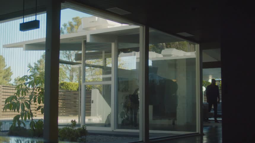 A man walking through a home with large windows