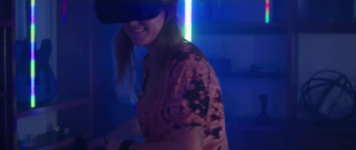 A man and woman laugh as they swing their arms while playing a virtual reality game at home