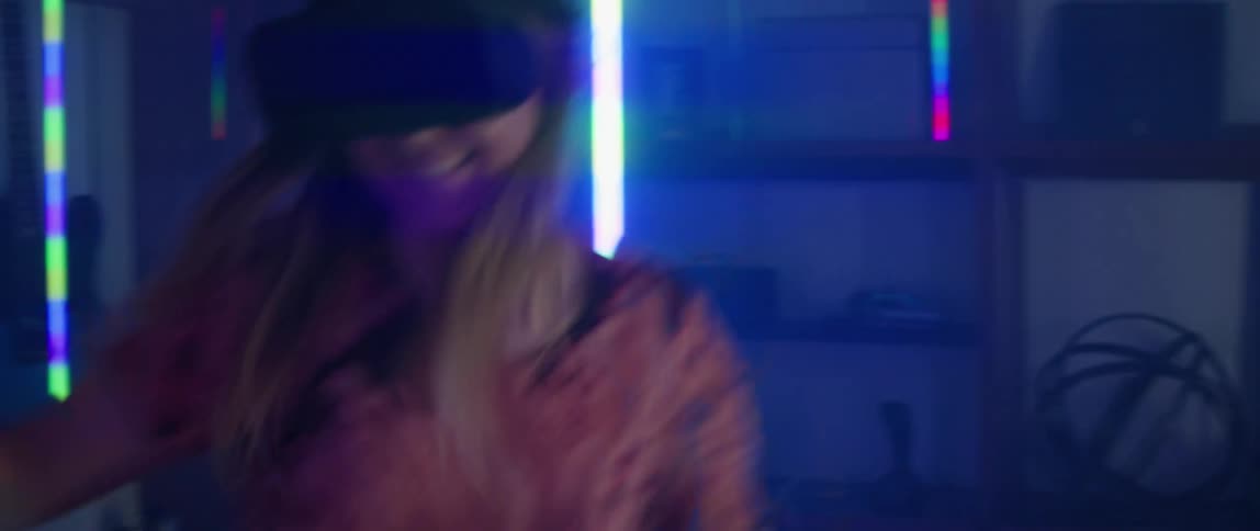 A man and woman laugh while playing a virtual reality game at home