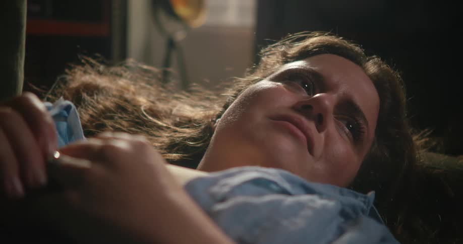 Woman lying down on a couch frowns slightly