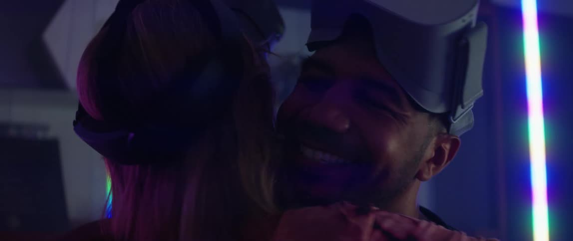 Man wearing a virtual reality headset moves forward to hug woman