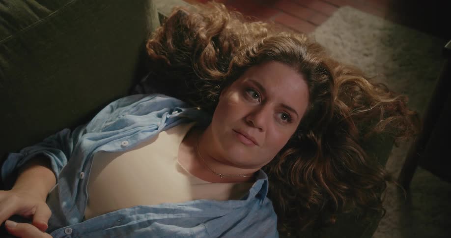 A woman is laying on a couch in her house