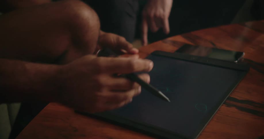 A group of men take turns drawing on a tablet