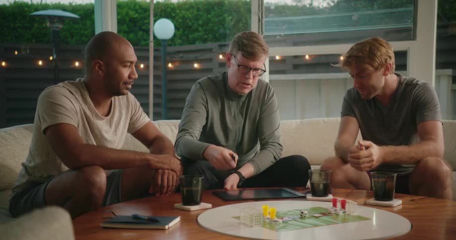 Group of friends relaxedly sitting on a couch at home playing a tabletop game