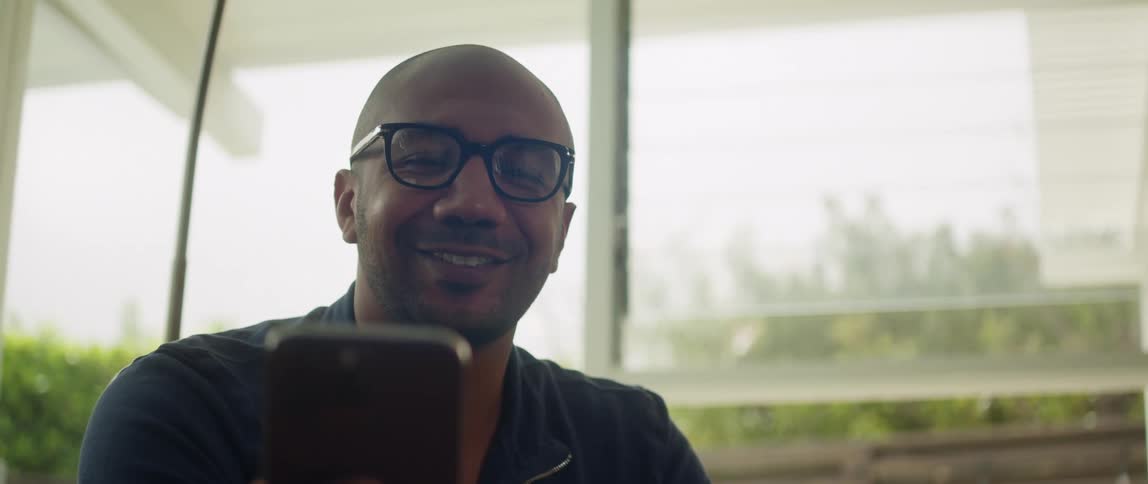 A man smiles as he talks on his phone
