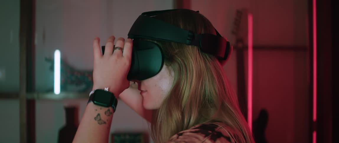 Blonde woman with smart watch and tattoo puts on virtual reality headset