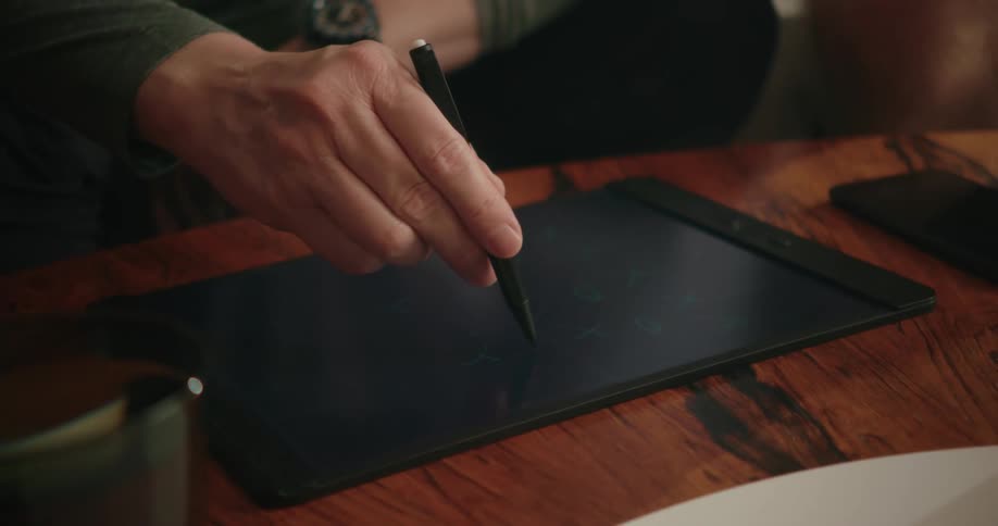 A man is drawing on a tablet while sitting on a couch