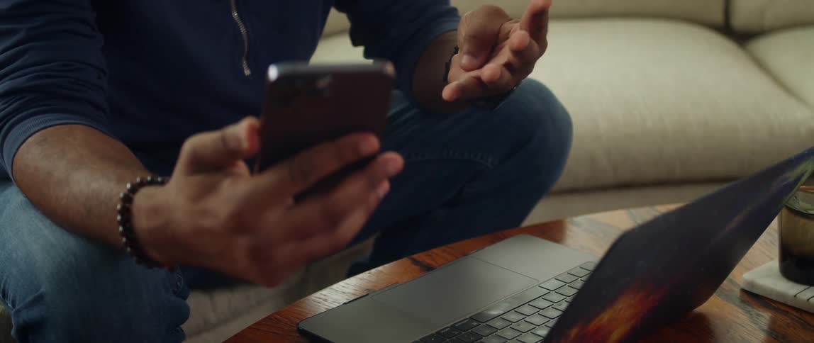 A man holds his smartphone and counts with his hand before putting it down on the table and rubbing his hands