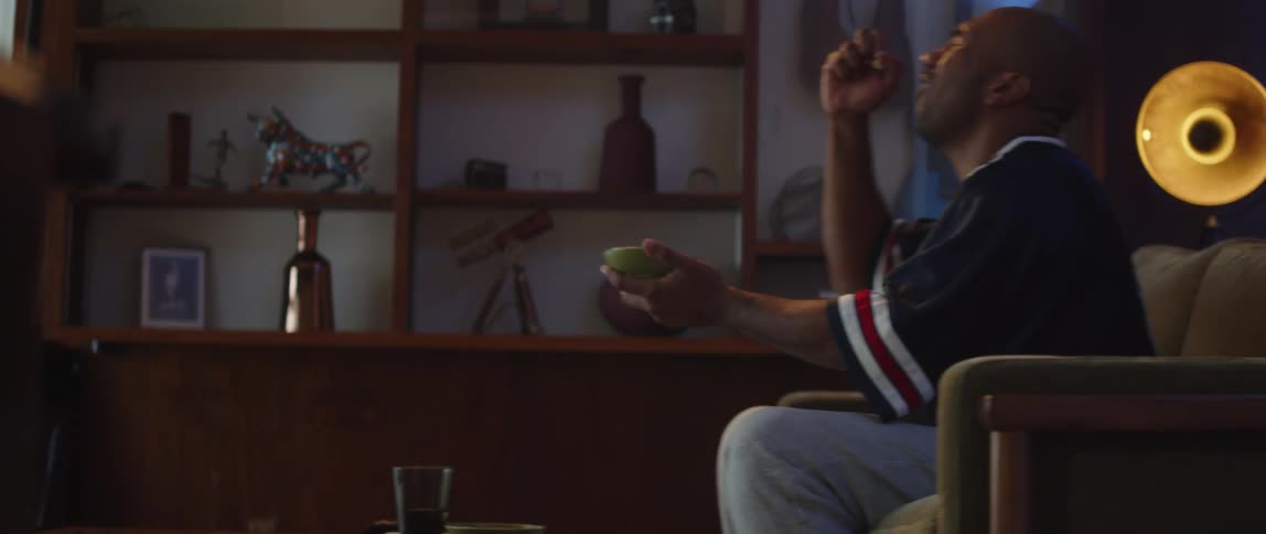 A man cheering for his sports team while watching television on a living room sofa