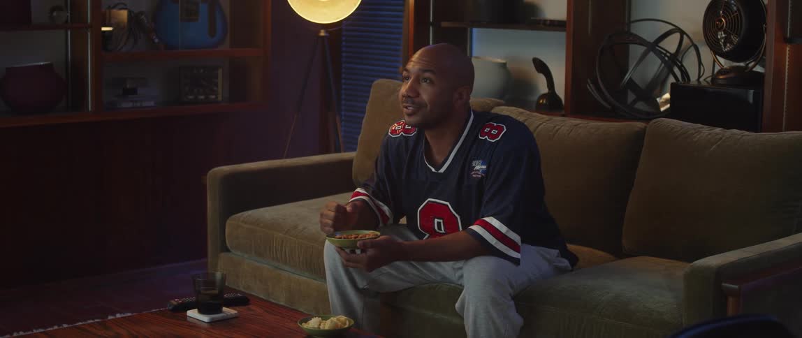 A man is eating snacks and watching television