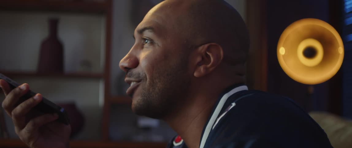 Close up of the face of a young man sitting on a couch at home talking on the phone