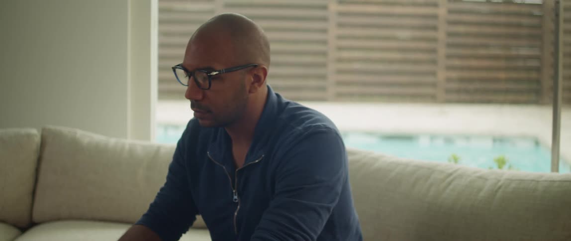 A man is sitting on a couch typing on a laptop computer on the table in front of him