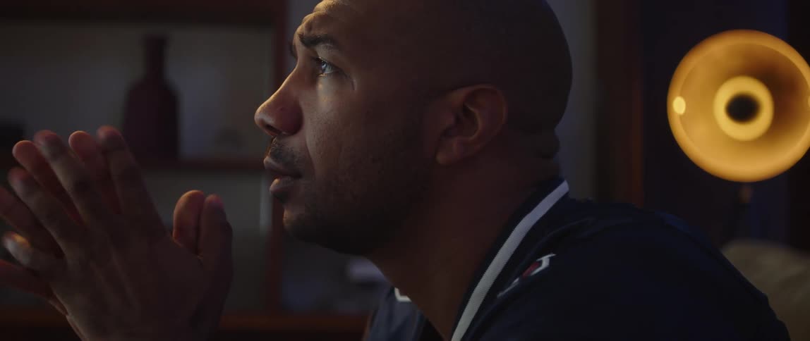 Young man sitting on a couch at home nervously watching sports