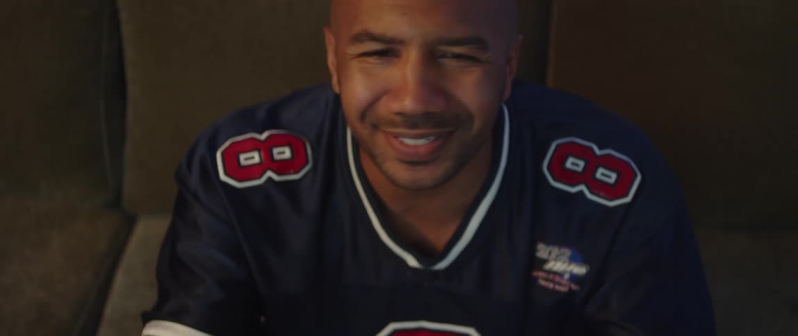 Close up of the face of a man sitting on a couch at home having an argument with the television while watching sports