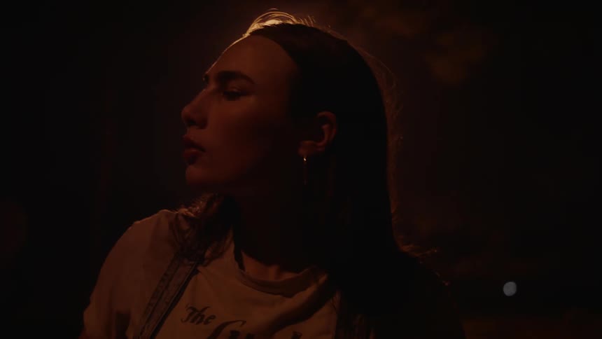 A young woman nervously looks around outside at night