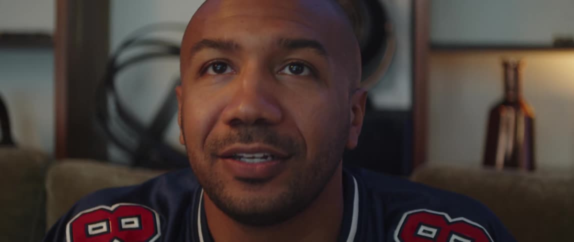 Close up of the face of a young man sitting on a couch at home celebrating while watching sports