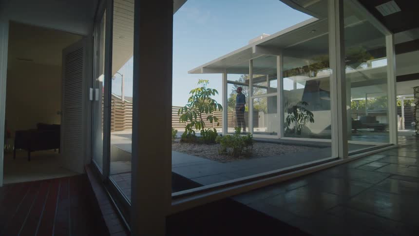A man is standing in his house and looking out the window