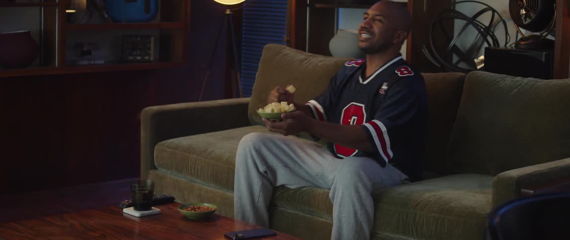 A man is sitting indoors and eating a snack