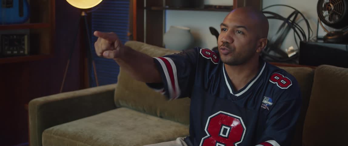 Young man sitting on a couch at home watching sports celebrates excitedly a good play