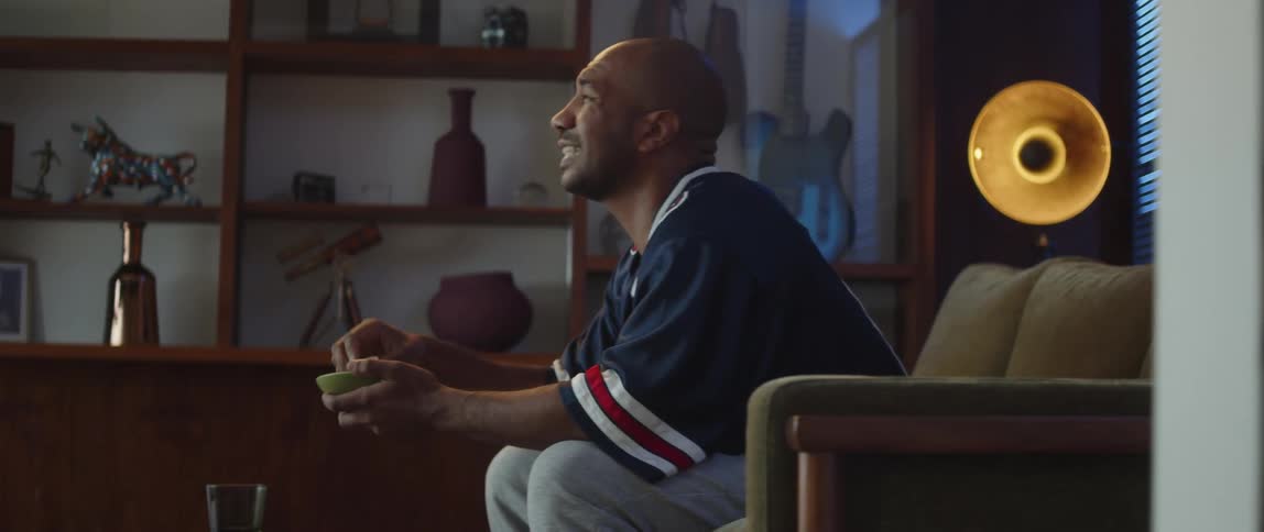 A man watching sports at home reacts to the game on the TV