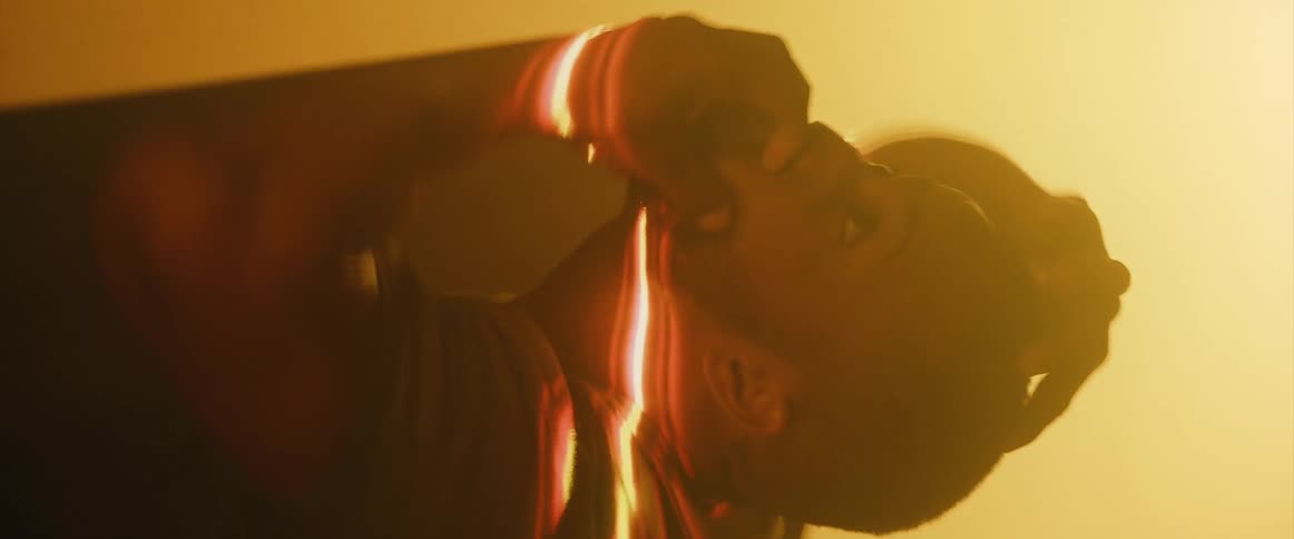 A man playfully waves his arms and hands through a thick plane of orange light