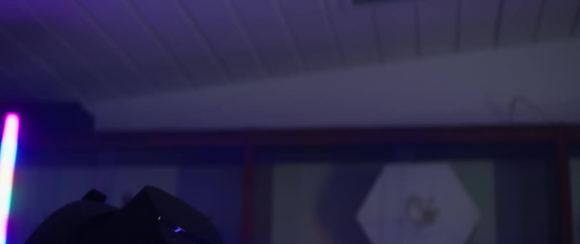 A girl wearing a virtual reality headset high fives with a man in a room with colored lights