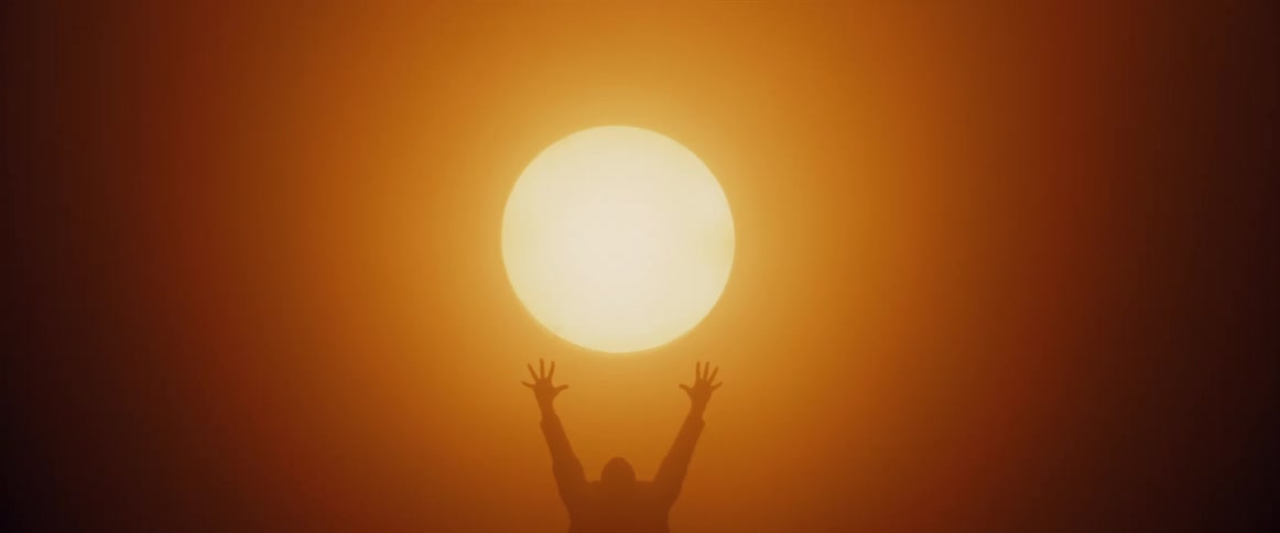 Silhouette of a man wearing a trenchcoat raising his arms towards a giant glowing sunlike sphere