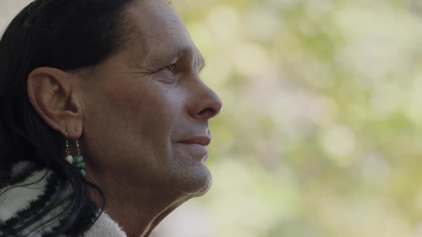 A native american man gazing into the distance and smiling softly