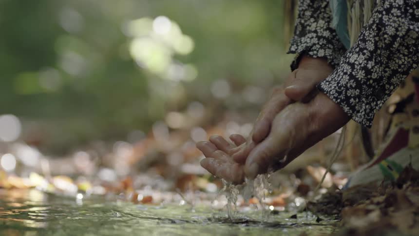 A man rinsing his hands in a stream