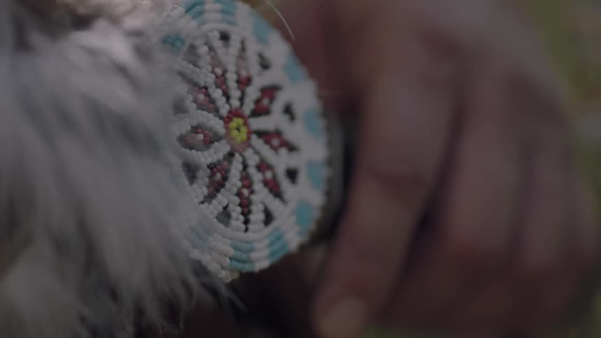 A beaded feather fan in someone's hand