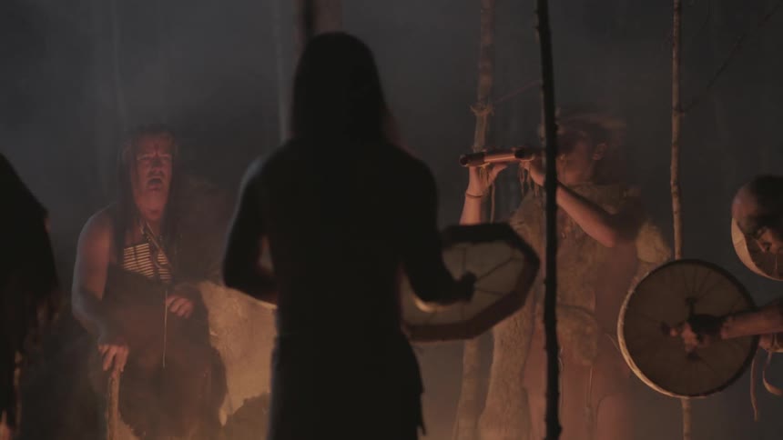 Native americans playing musical instruments around a campfire