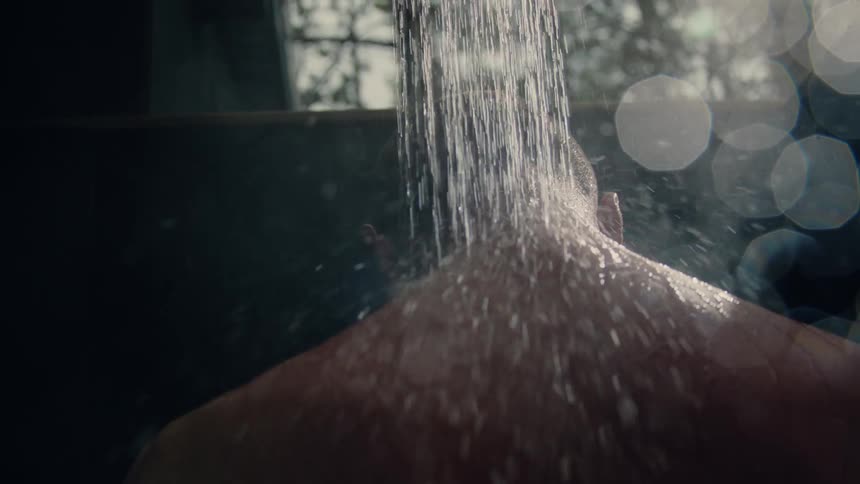 A man standing beneath a running showerhead