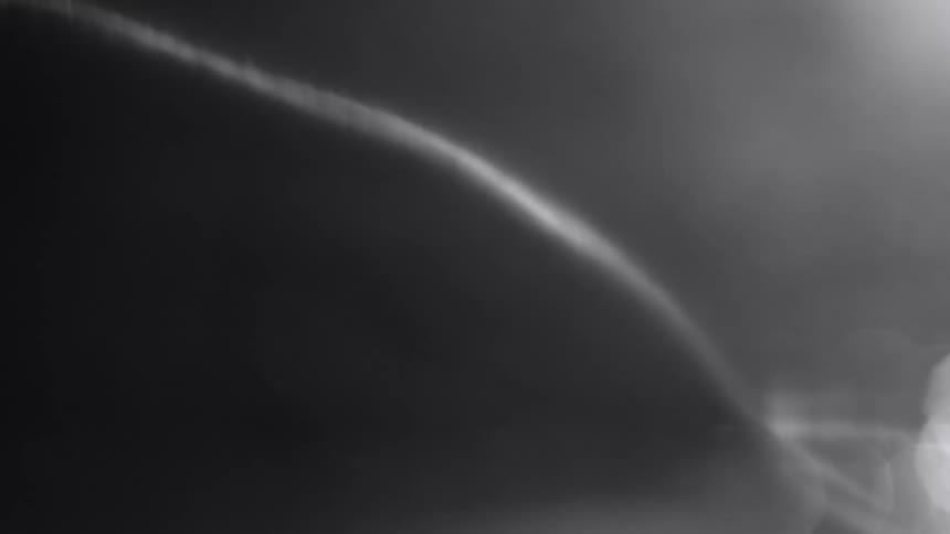 A piece of thread wiggles while magnified under a microscope