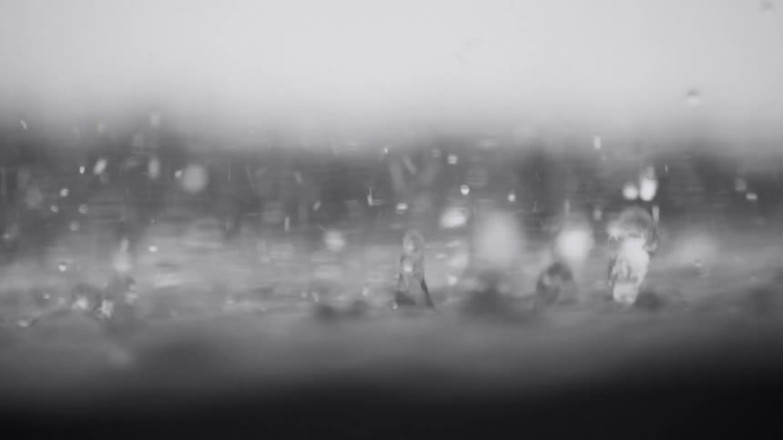 Droplets and spheres splash and bounce in the water as it rains