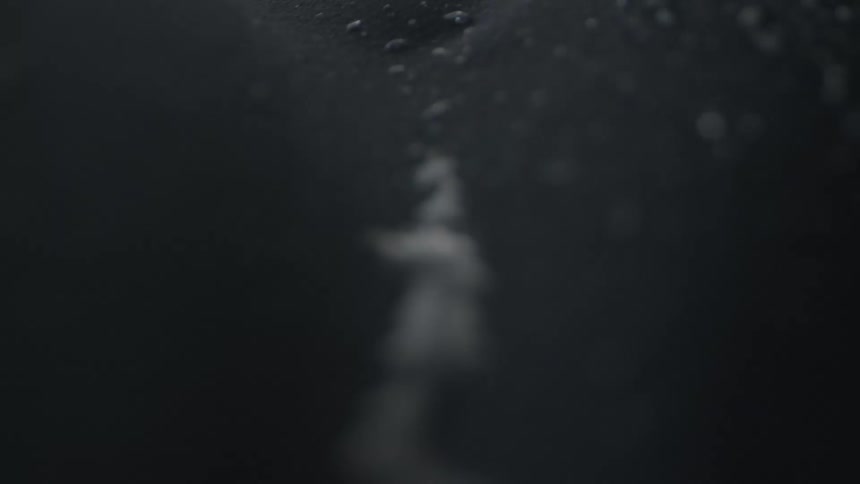 A black fabric with droplets of water rippled in between