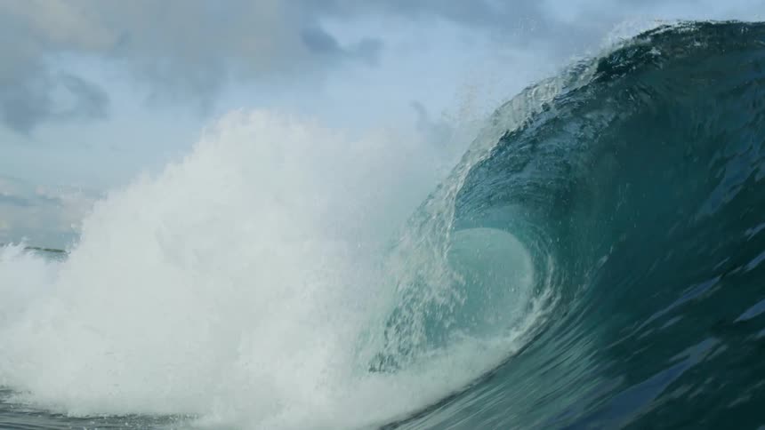 A huge wave rolls in splashing overhead and looking up from underwater