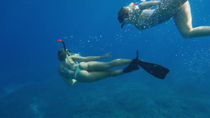 Two female snorkelers swimming in blue ocean water