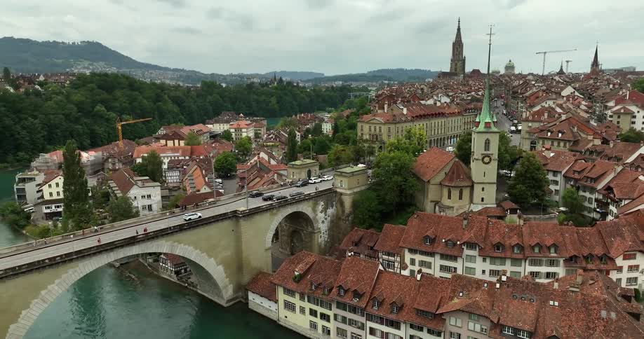 Aerial view of the tiled red roofs and towers on an european town near a bridge over a river