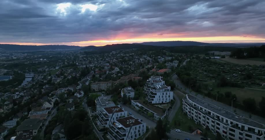 An aerial view of apartments and buildings in a city as the sun sets
