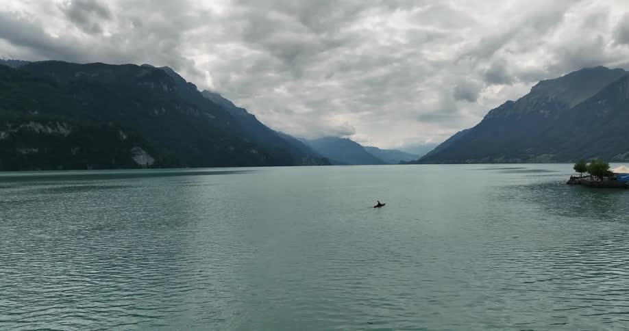 A person in a kayak paddles across a lake on a cloudy day