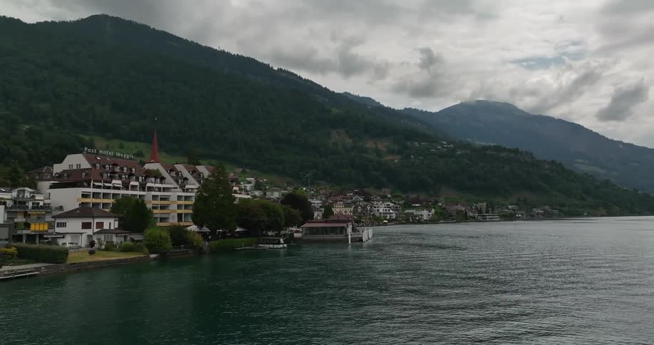 Town sits between forested mountains and water on misty overcast day