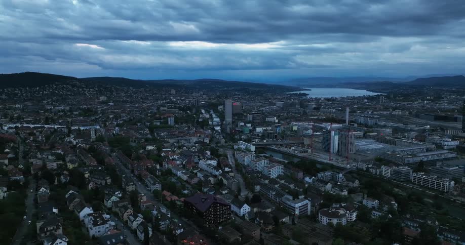 Aerial view of city buildings and distant lake at dusk