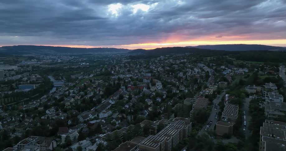 Aerial view of city buildings on hill slope at sunset