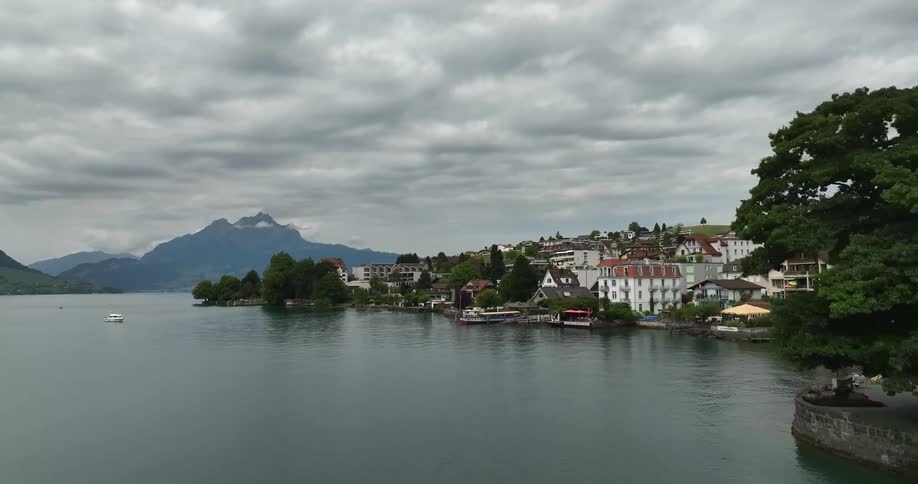Boat moves through water a short distance from town on shore with misty mountains in the background