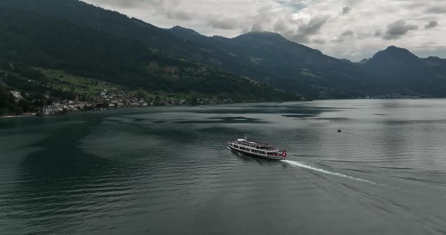 A ferry makes its way across a waterway in the mountains to a town on the shore