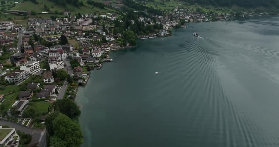 An aerial view of a small village is shown where houses are crammed together and there is a lake to the right of it